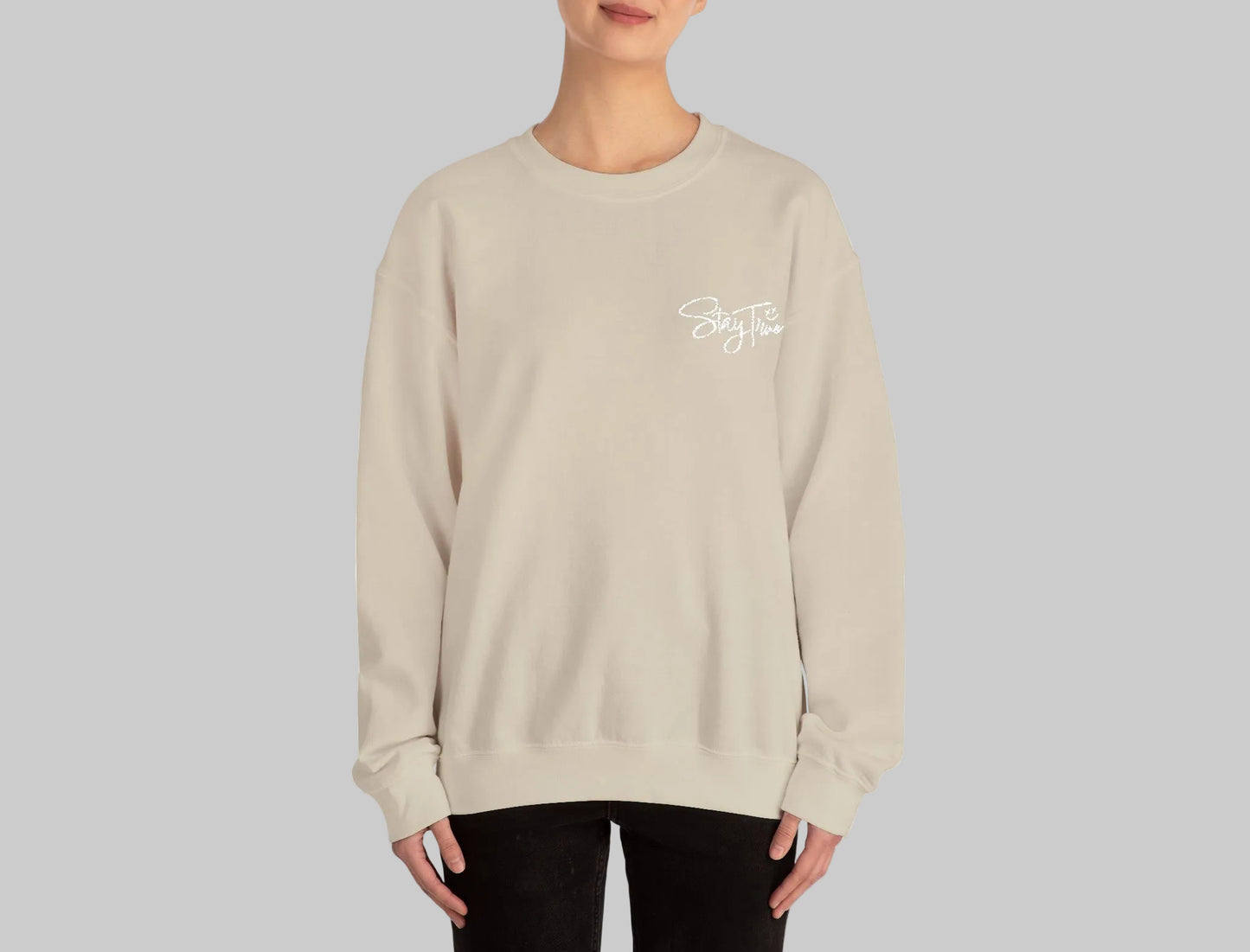 Person wearing a beige sweatshirt with a small graphic on a white background