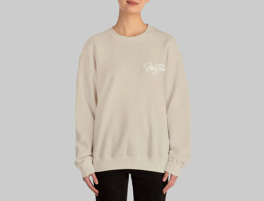 Person wearing a beige sweatshirt with a small graphic on a white background