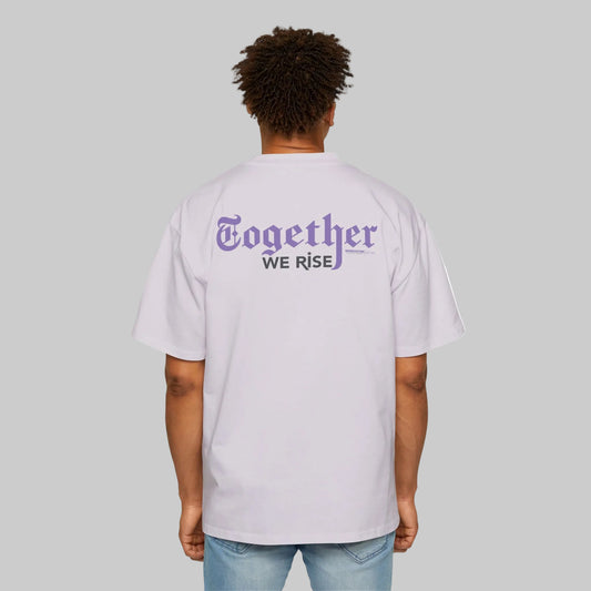 Person wearing a light purple t-shirt with 'Together We Rise' text on the back, standing against a gray background. Paired with light washed jeans.